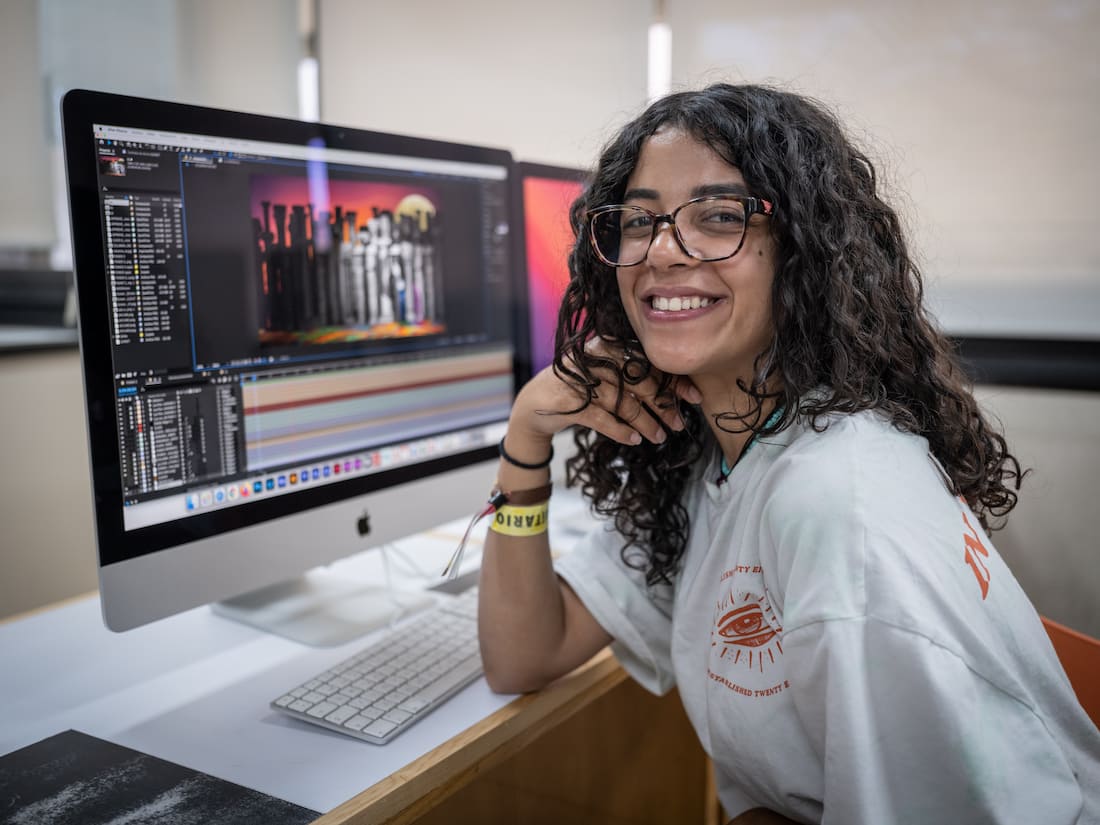 Joven trabajando en una composición visual animada en un software profesional de edición, en ambiente académico.