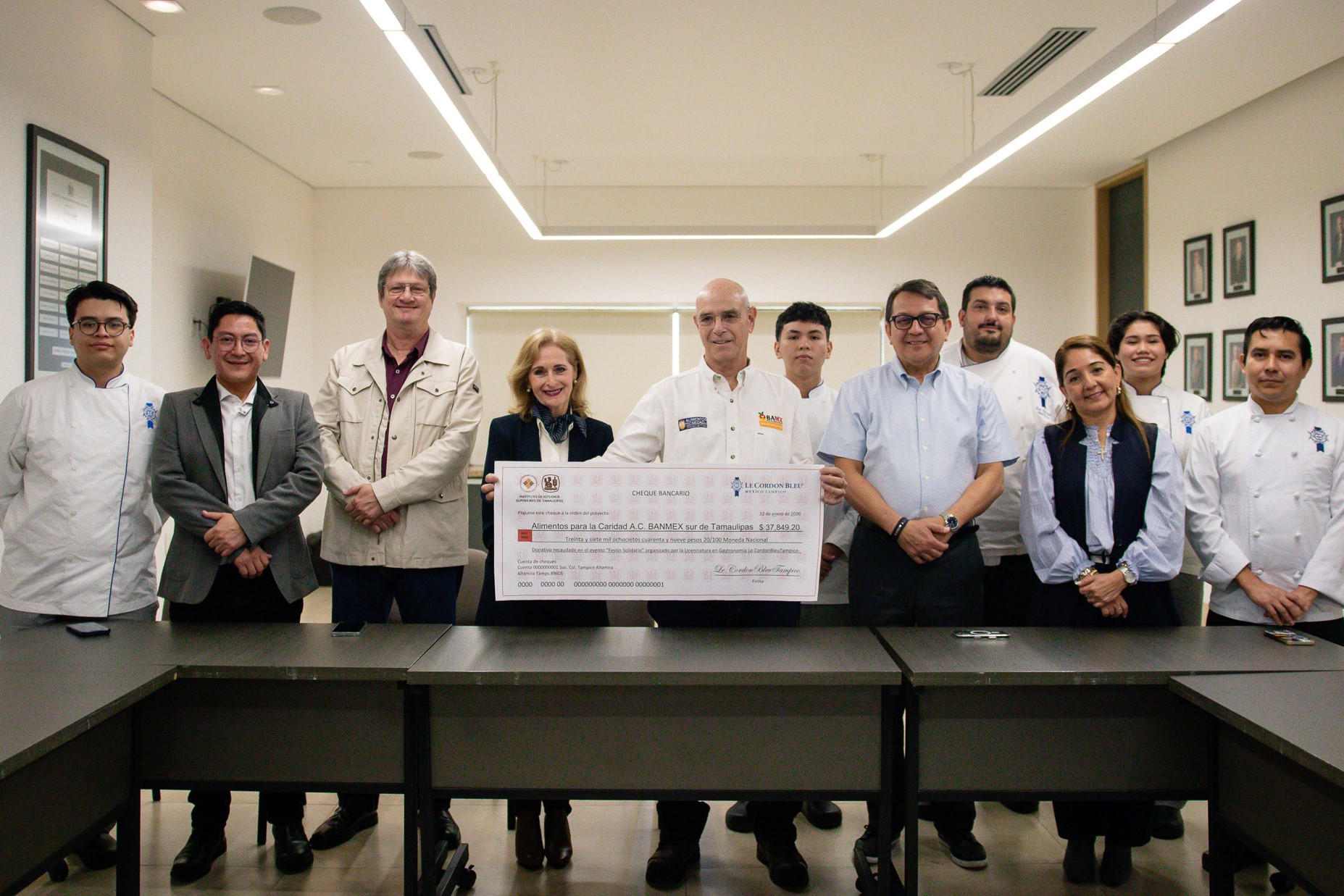 Autoridades académicas y alumnos de Gastronomía entregando un cheque.